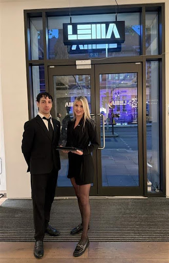 7 Common Event Staffing Challenges and How Brand Ambassadors Fix Them Two professionally dressed event staff members stand at the entrance of a modern venue, with one holding a tray and both smiling while welcoming guests
